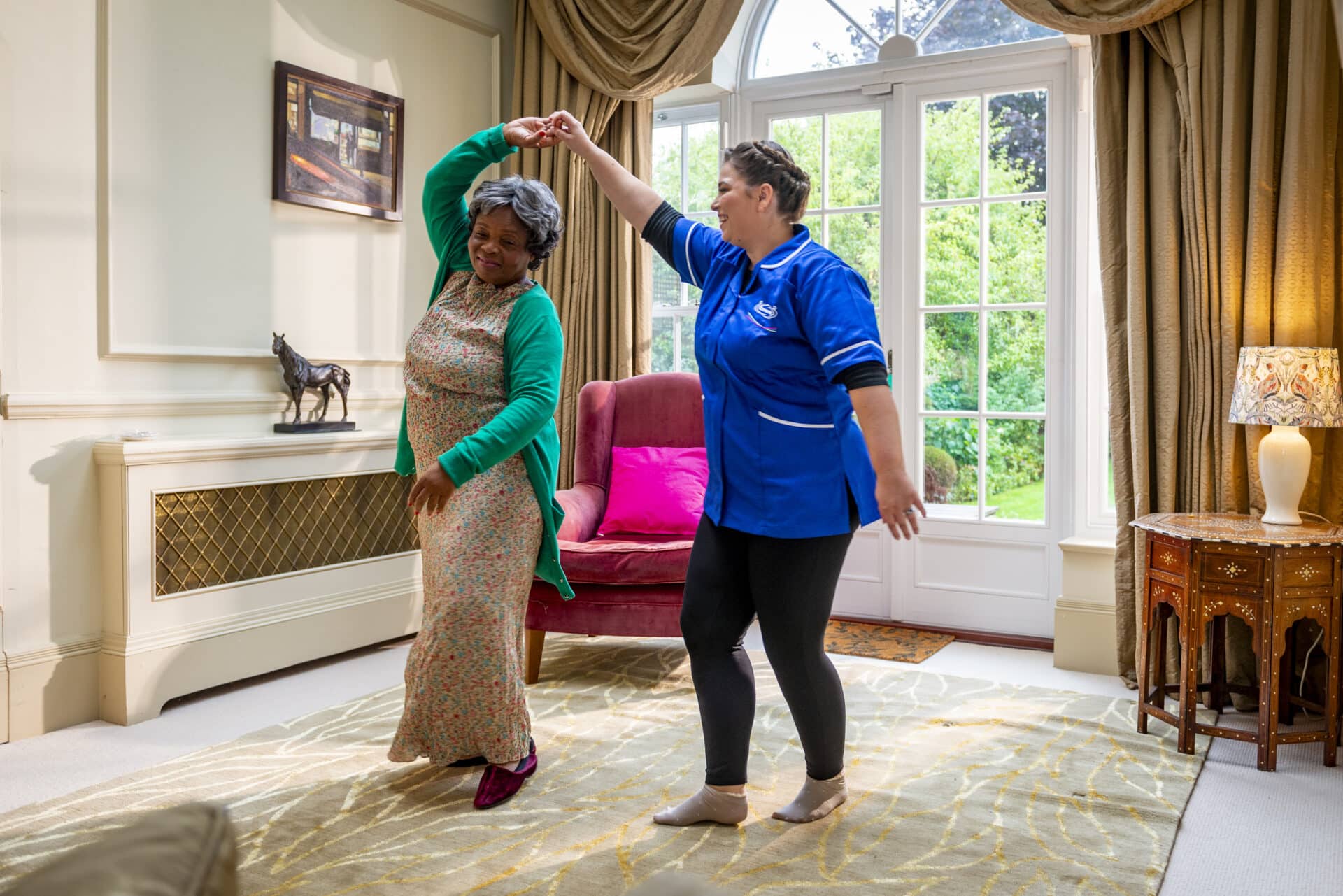 Two women dancing in a bright common area.