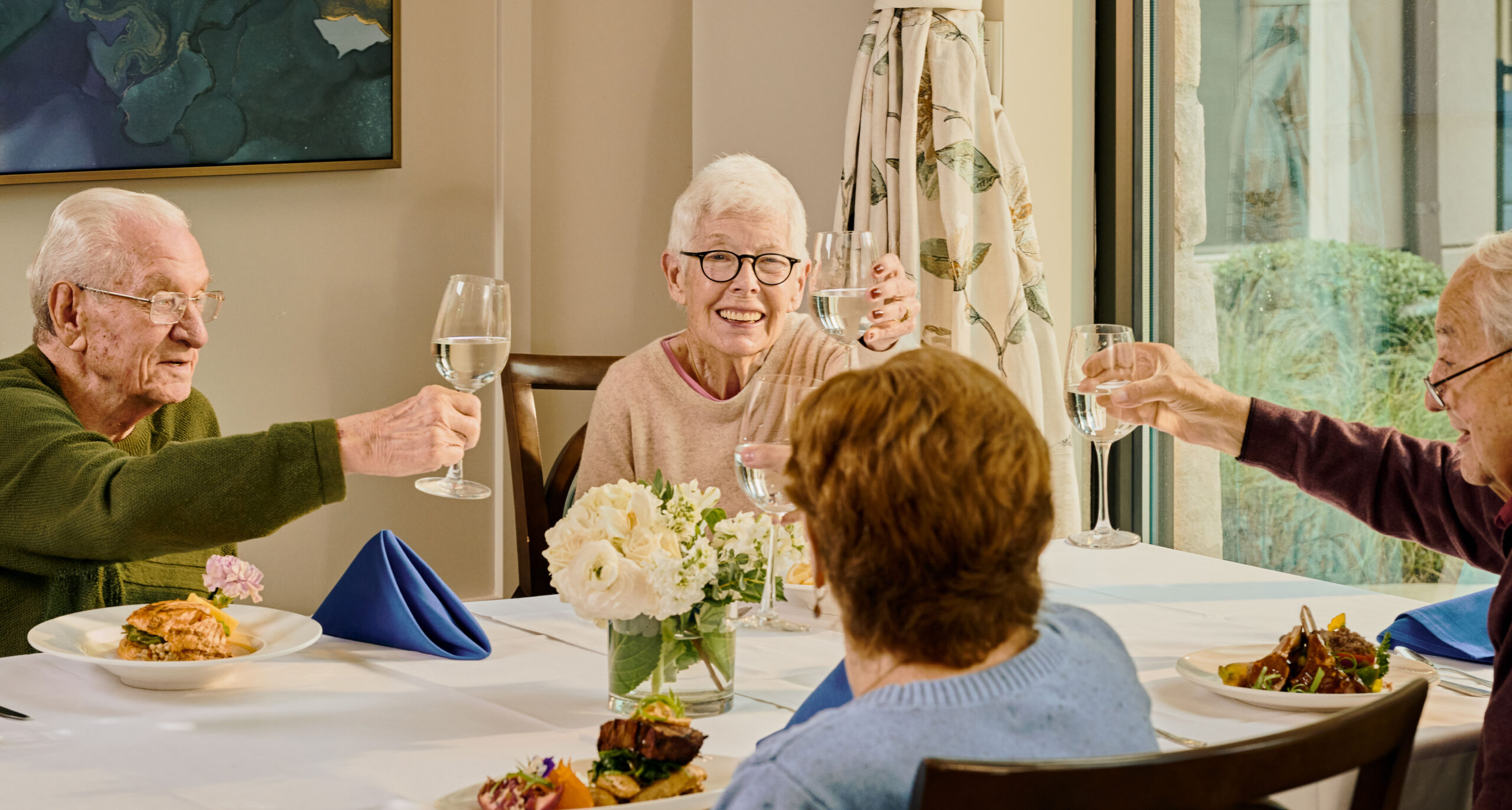 Residents toasting with drinks at a dining table