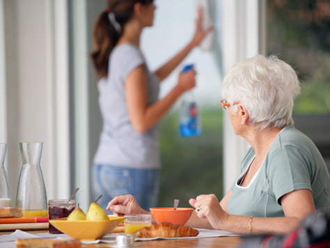 Resident enjoying meal while staff cleans nearby