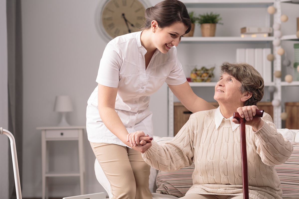Nurse assisting elderly woman in a cozy room