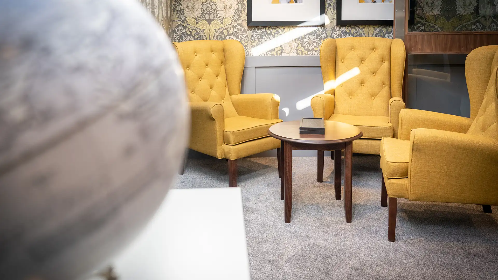 Cozy common area with yellow armchairs and a round table.