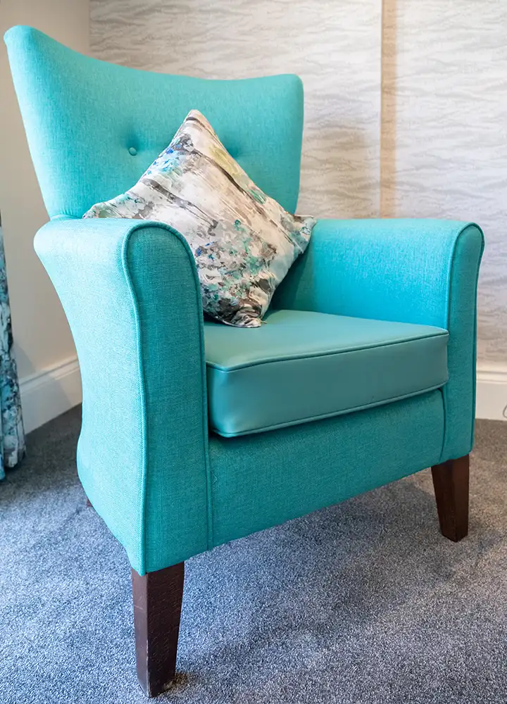 Bright turquoise armchair with a decorative pillow