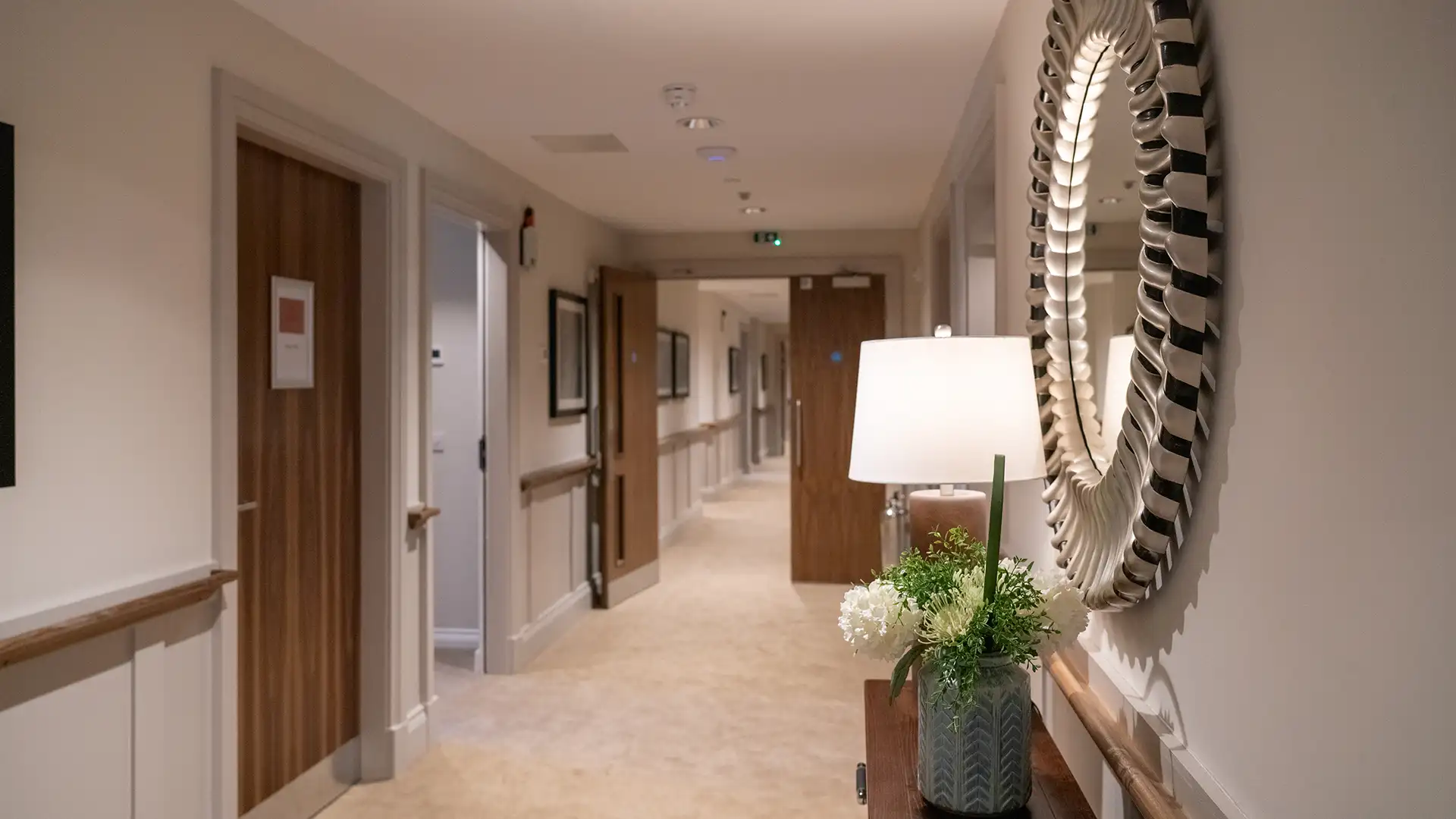 Well-lit hallway with decor and a lamp.