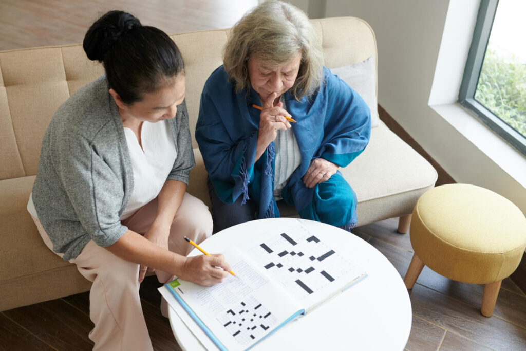 Staff and resident engaging in a crossword puzzle
