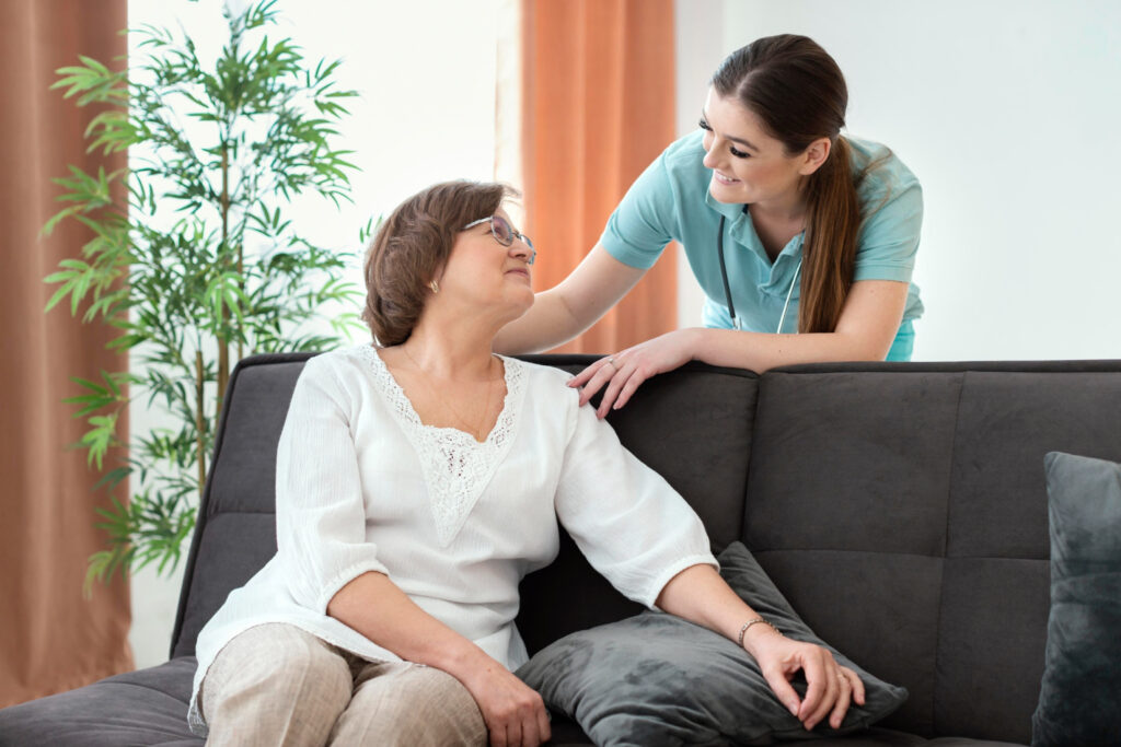 Caregiver interacting with a senior resident on a couch.