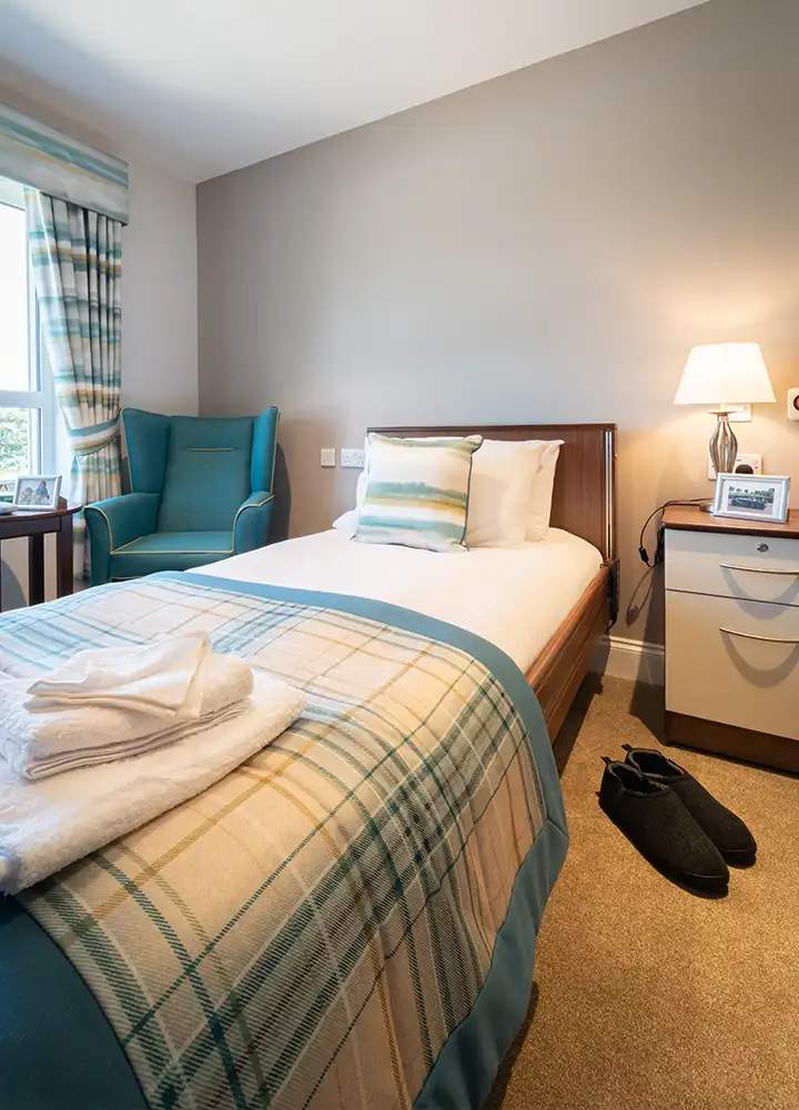 Cozy private resident room with bedding and a chair.