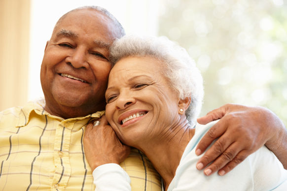 Two seniors smiling and embracing each other.