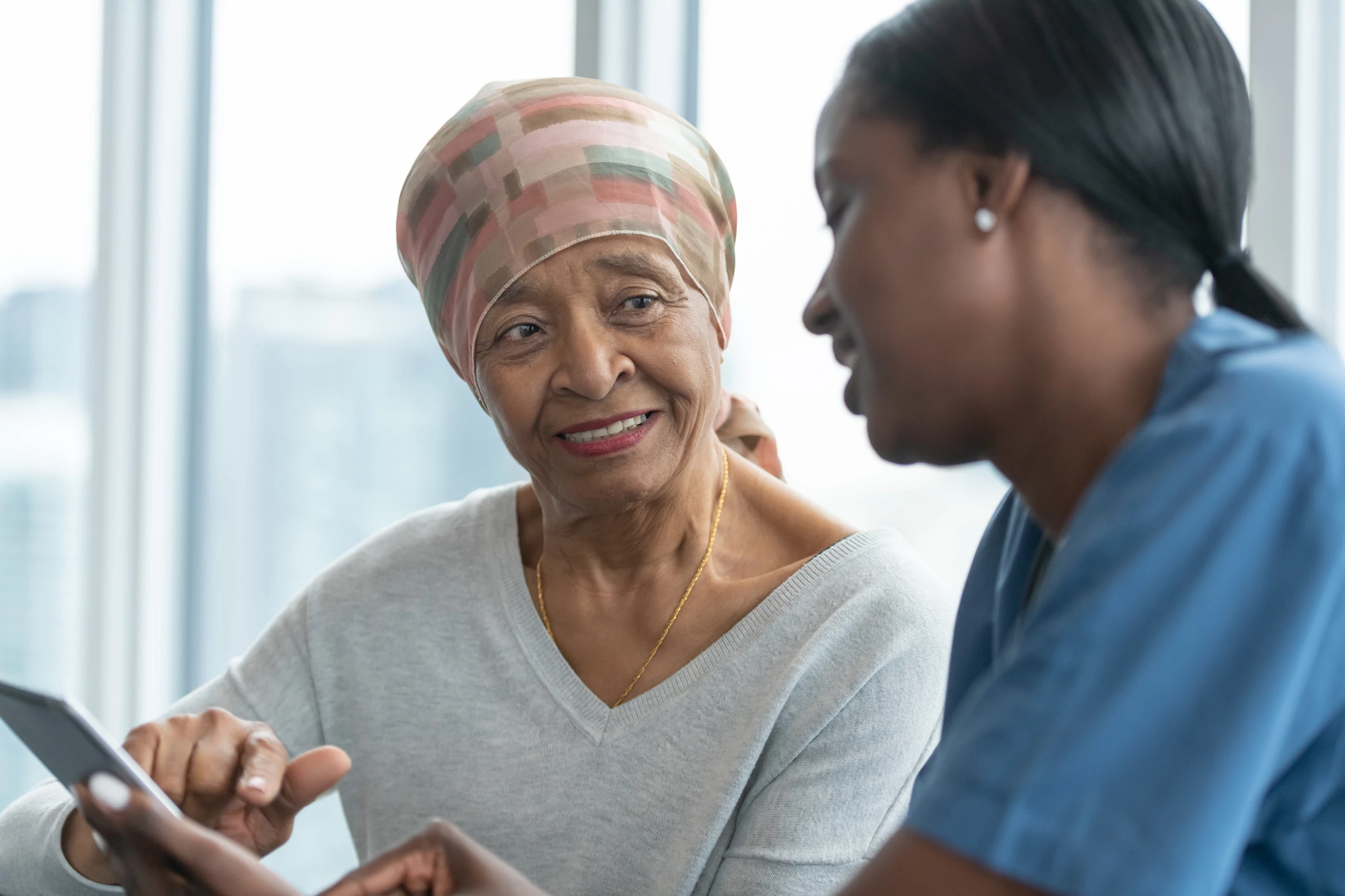 Caregiver assisting a senior woman with a tablet.