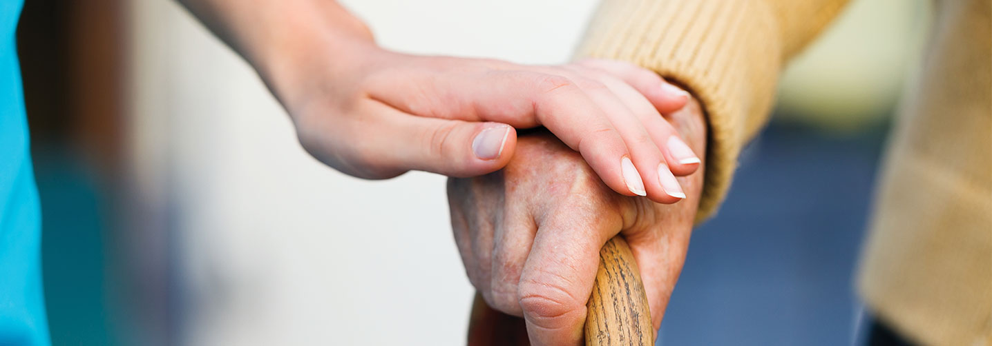 Close-up of hands holding a cane.