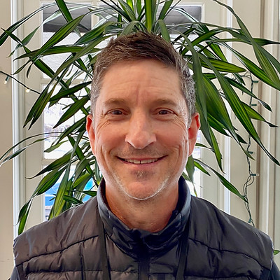 Smiling man with plants in background.
