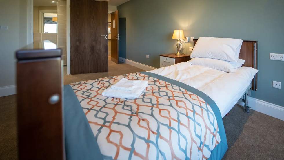 Well-furnished resident room with a bed and lamp.
