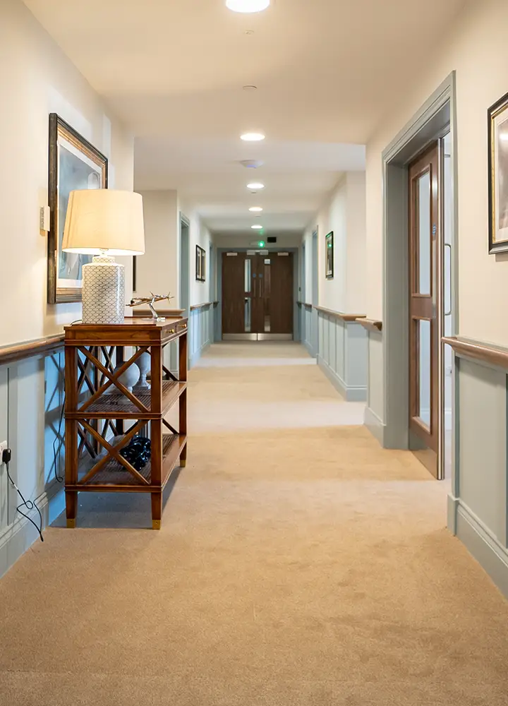 Well-lit hallway with art and a lamp.