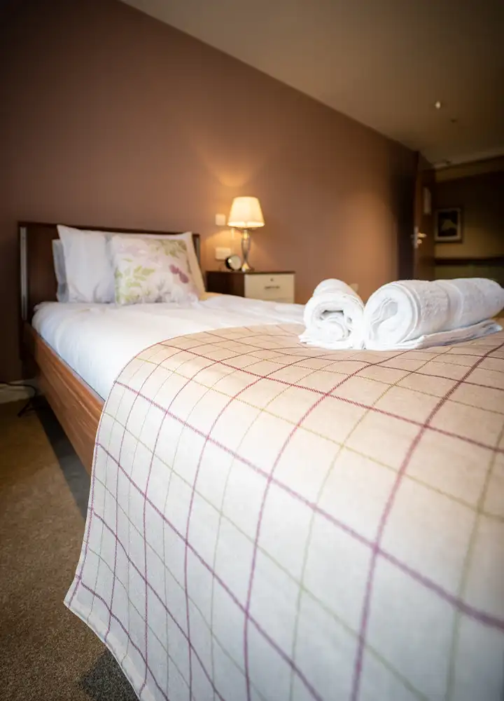 Cozy, well-furnished resident room with bed and towels.