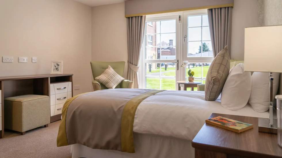 A cozy resident room with a bed and chair.