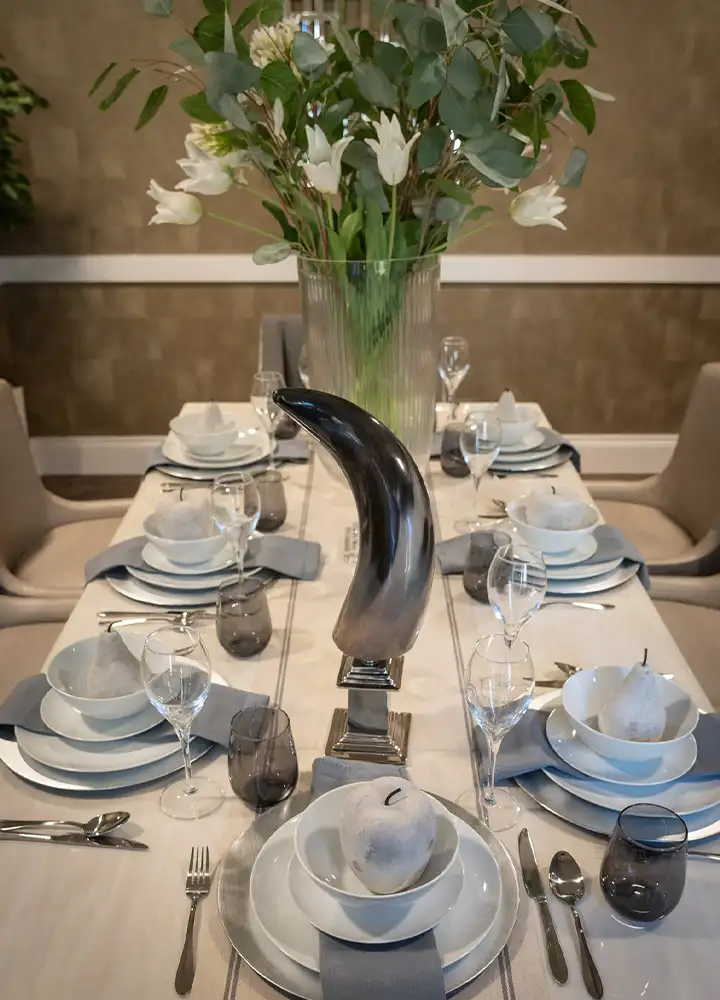 Elegant dining table set with flowers and dishware.