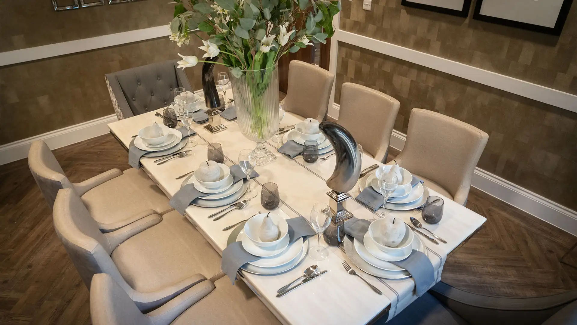 Elegantly set dining table with floral centerpiece.