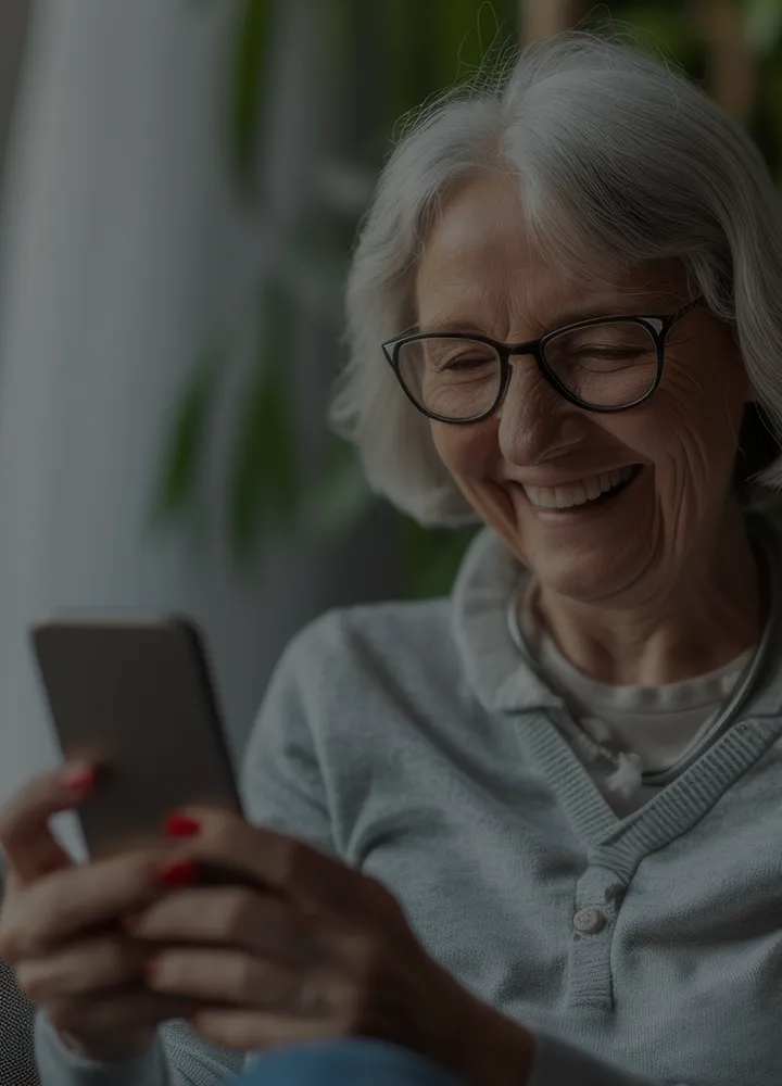 Senior woman smiling while using a smartphone.