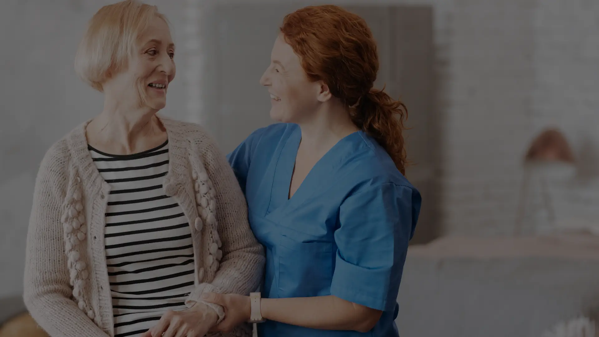 A caregiver smiles with a resident indoors.
