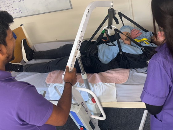 Healthcare staff assisting a resident with mobility equipment.