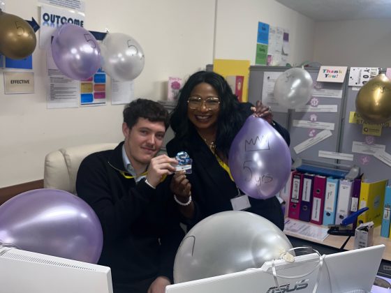 Staff celebrating with balloons and a trophy