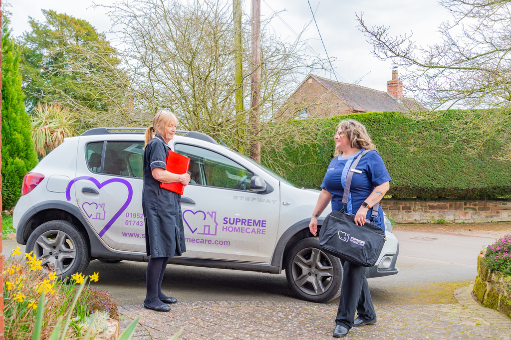 Two caregivers interacting near a vehicle