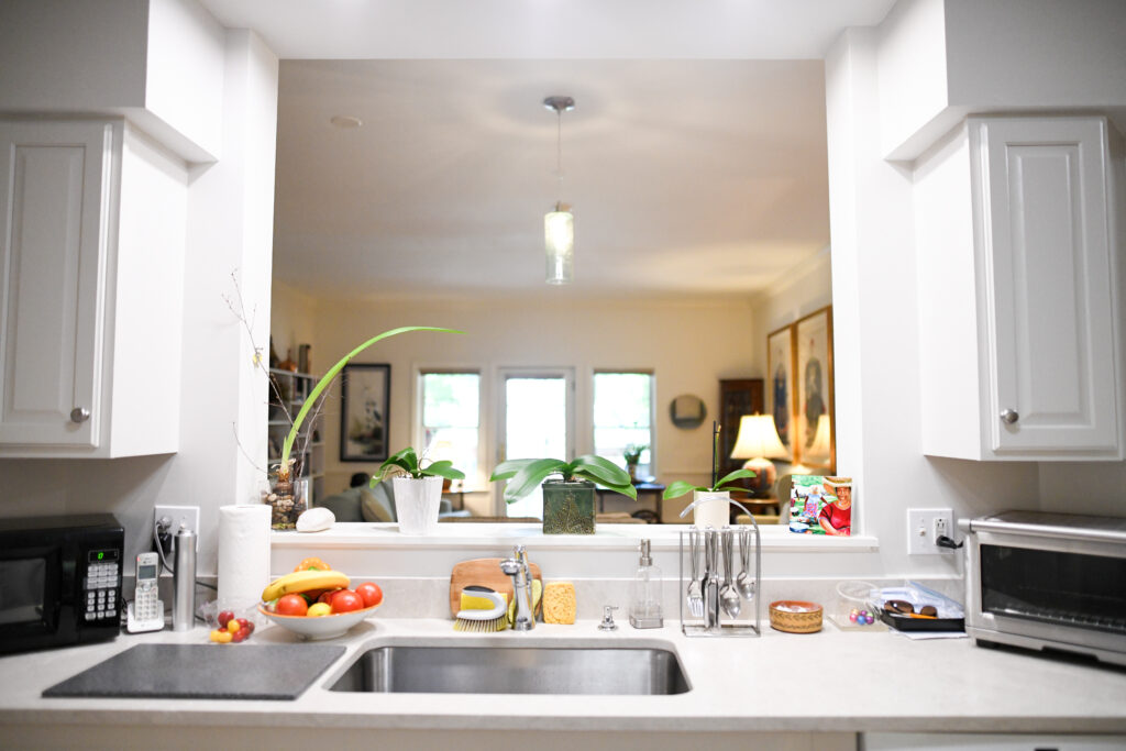 Bright kitchen space with fruits and a view into a living area.