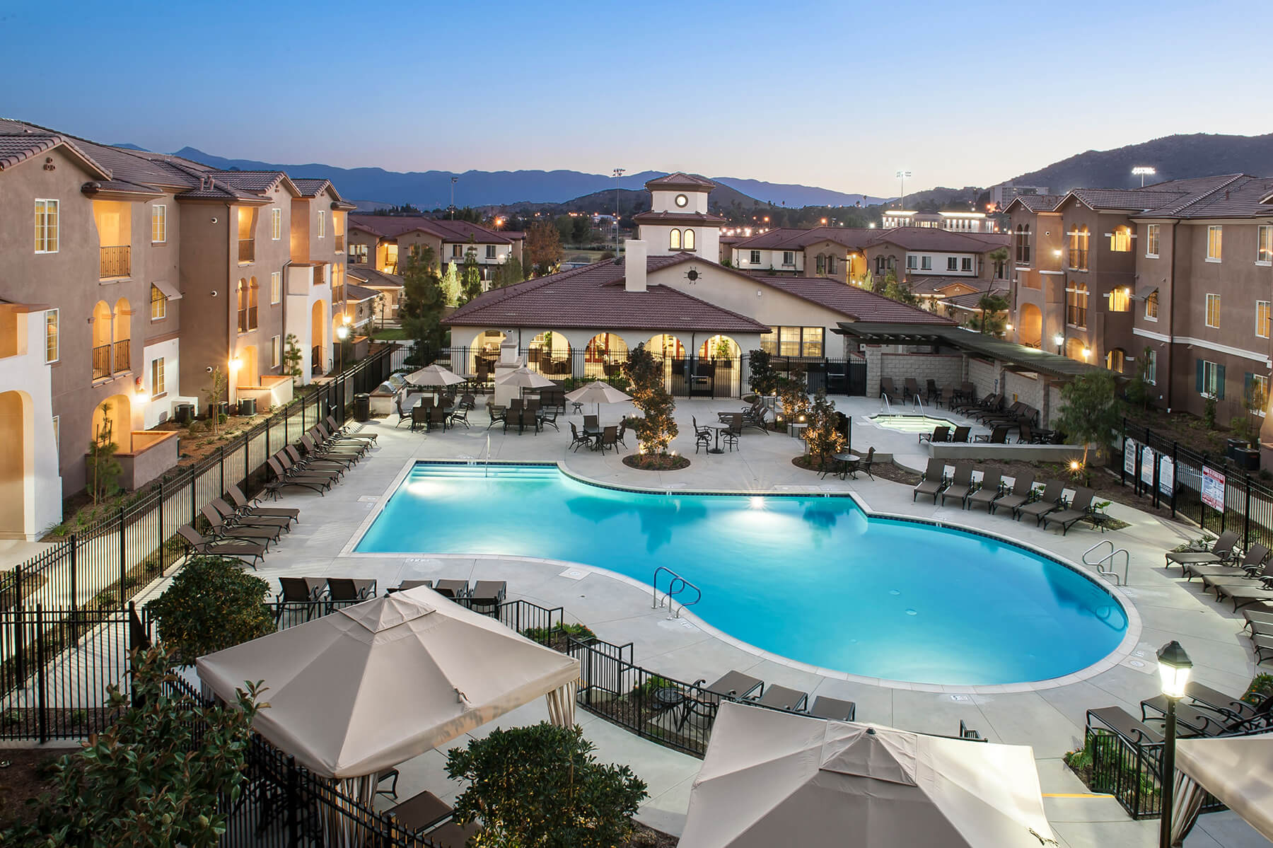 Outdoor pool area with seating and buildings in the background