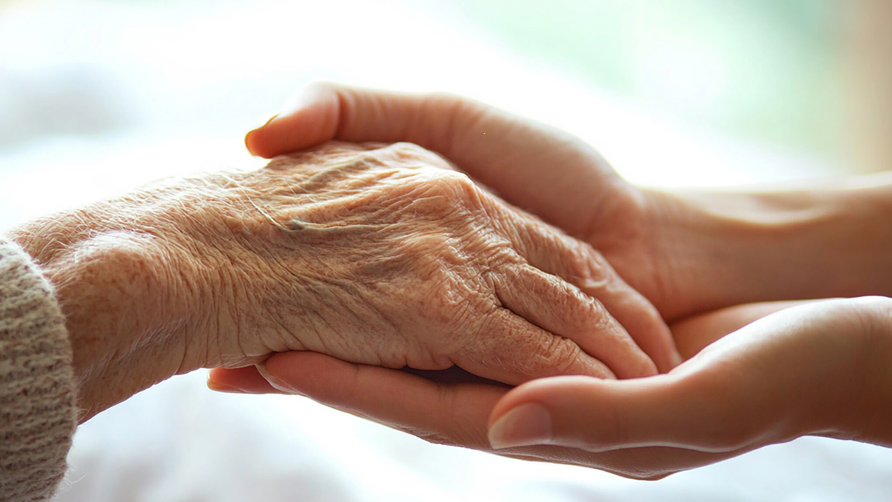 A caregiver holding an elderly person's hand.