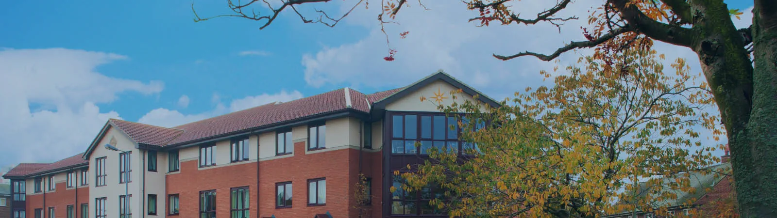 Exterior view of Berkeley House Care Home with autumn trees