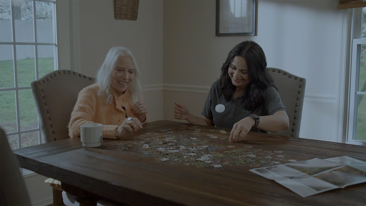 Resident and staff member working on a puzzle together