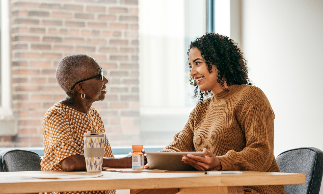 Two women talking at a table in an indoor space.