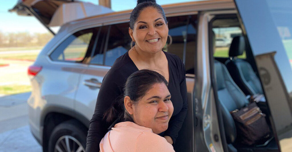 Two women by a vehicle in a parking lot