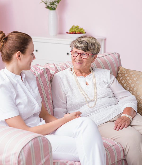 Caregiver conversing with a resident in a cozy common area.