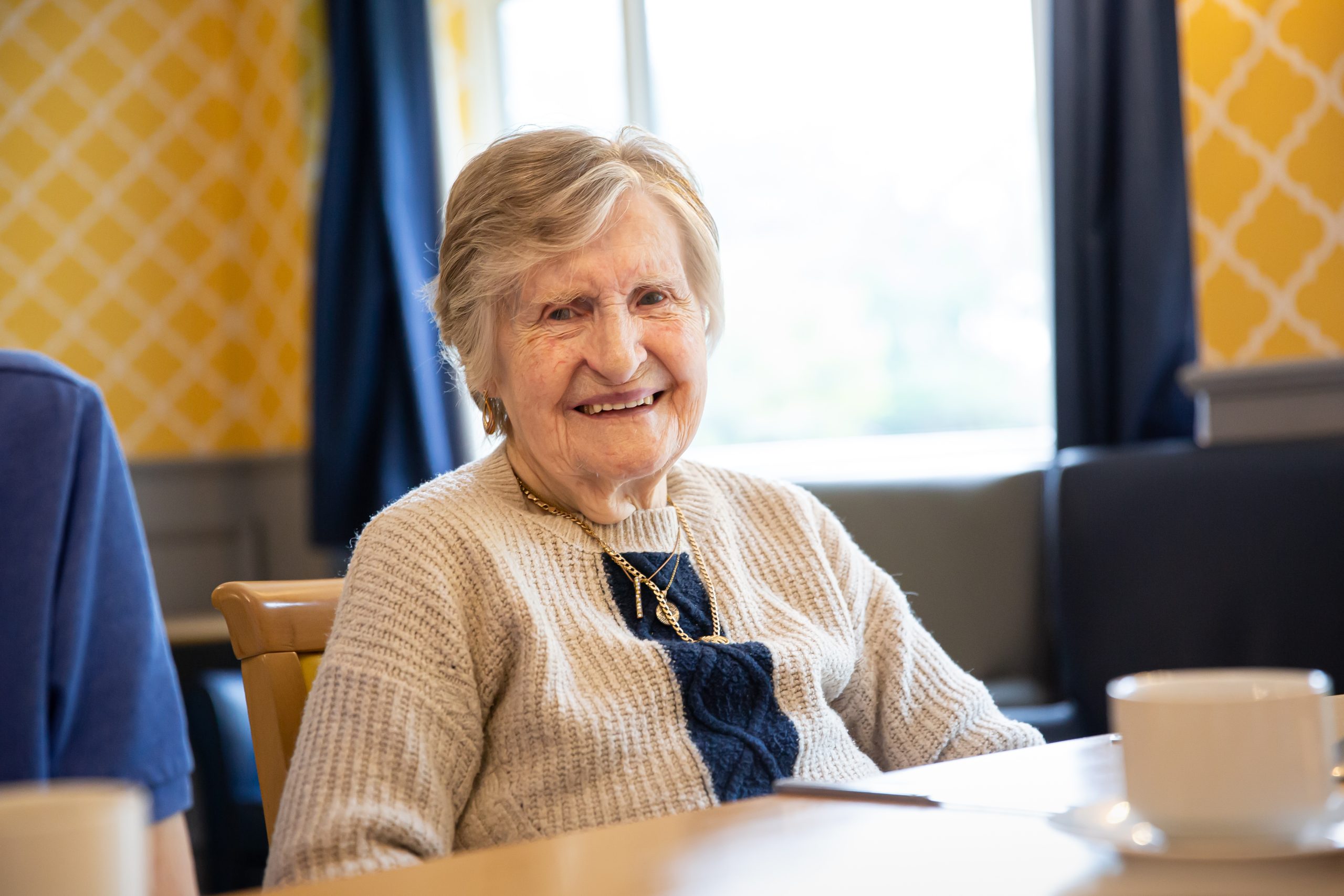 Senior woman smiling in a cozy interior setting.