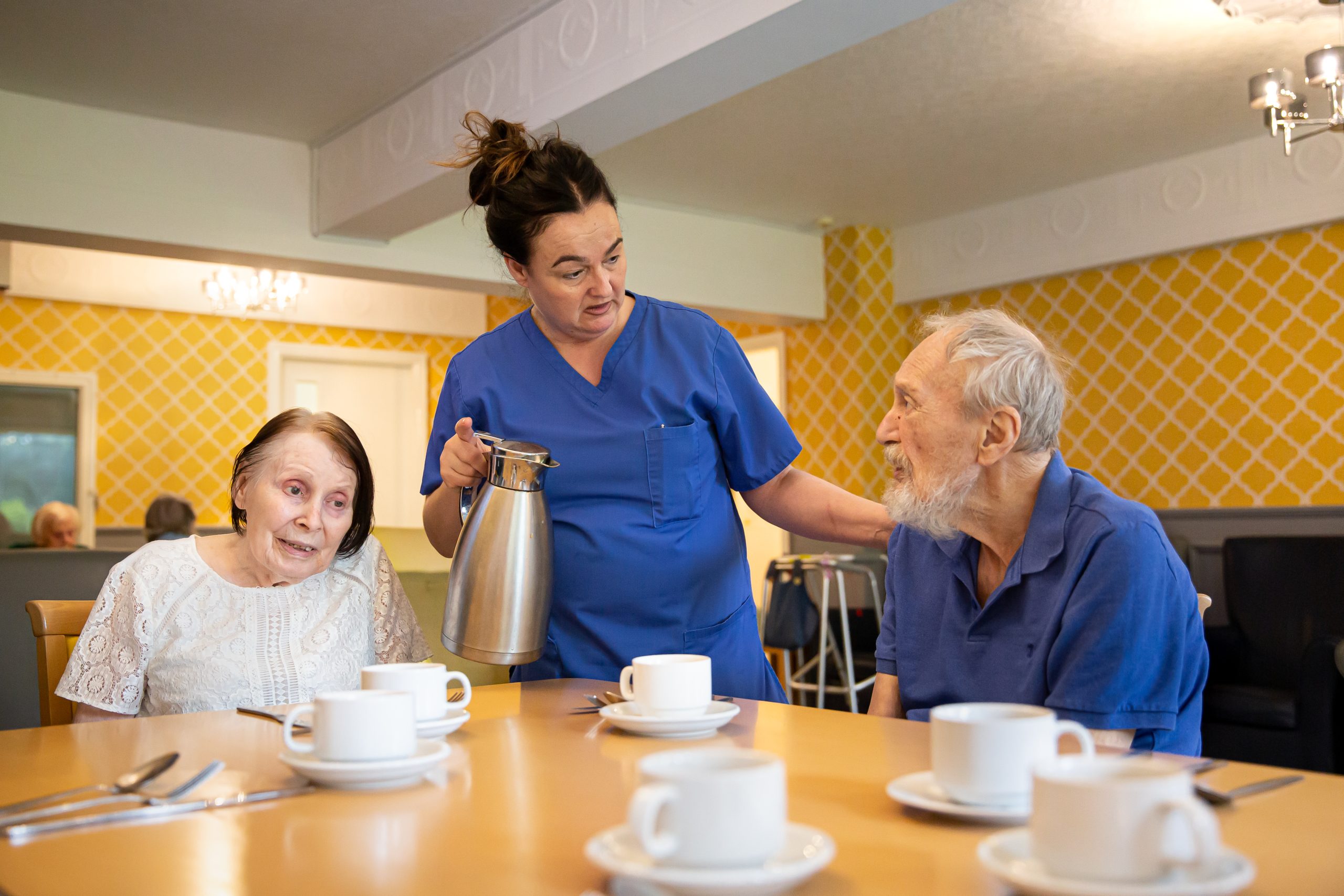Staff serving coffee to residents in a dining room