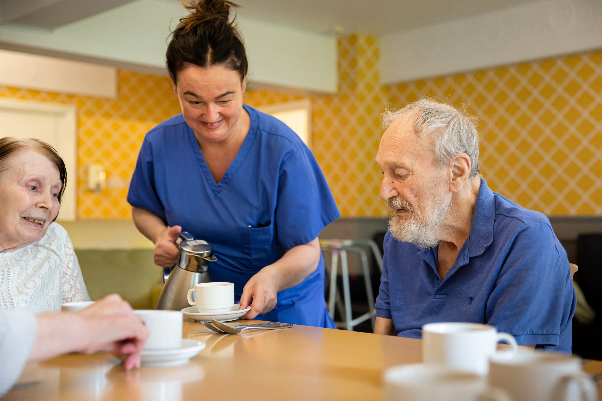 Staff member serving coffee to residents.