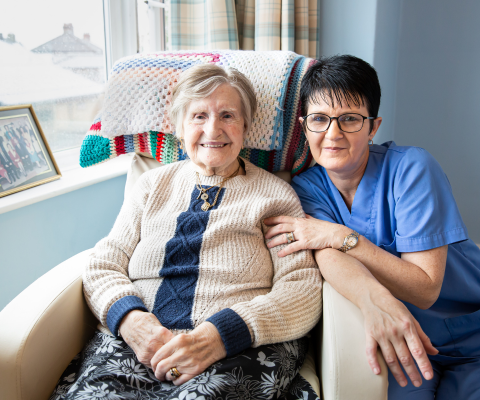 Senior resident and caregiver smiling together