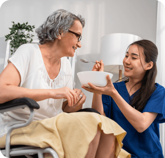 Resident enjoying food with staff assistance