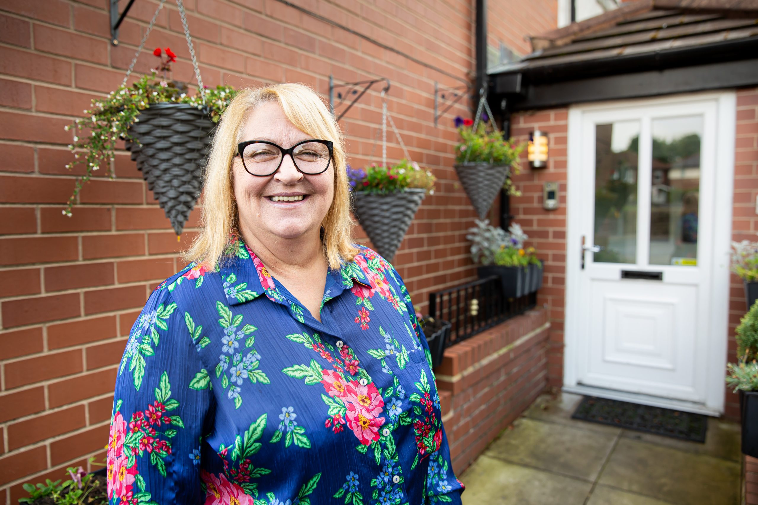 Resident smiling in a flower-filled outdoor space.
