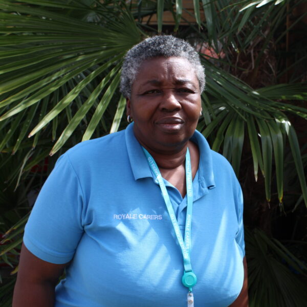 Staff member in a blue shirt outside with palms