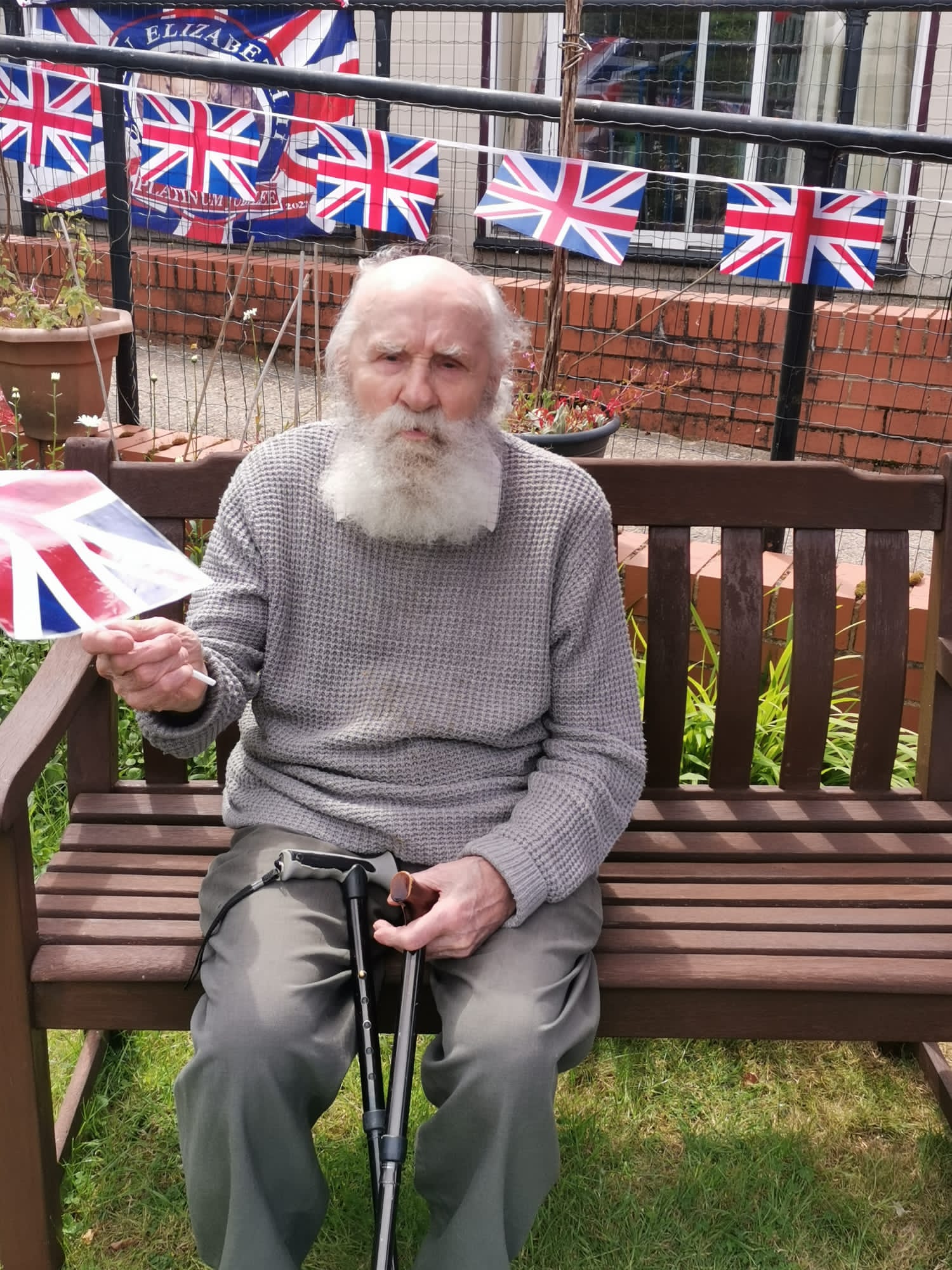Elderly man holding a card in a garden