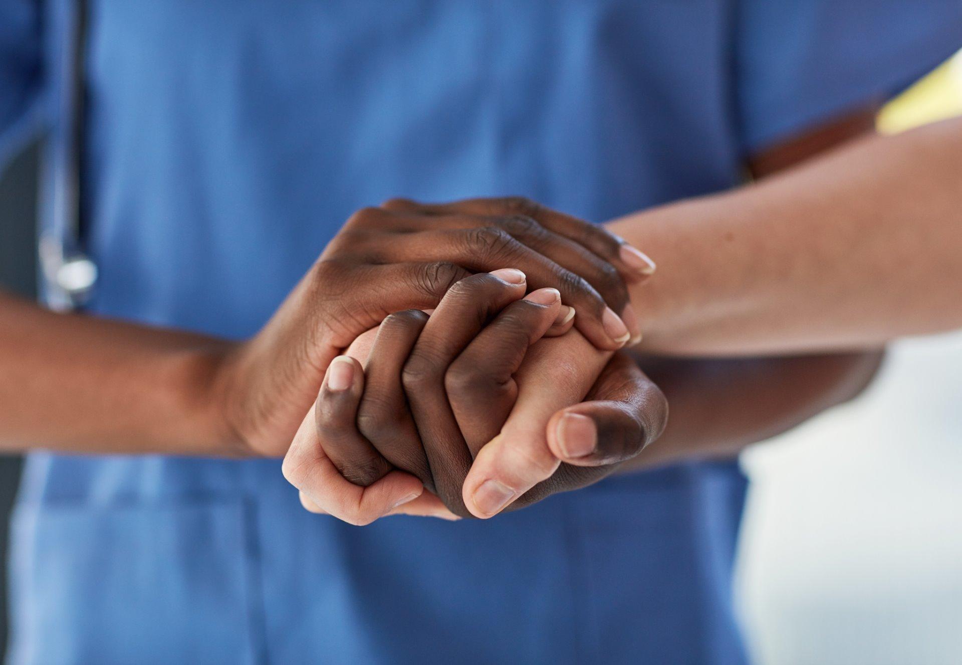 Close-up of healthcare workers holding hands.