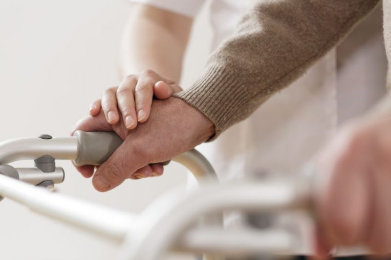 Hands of a caregiver and resident on a walker