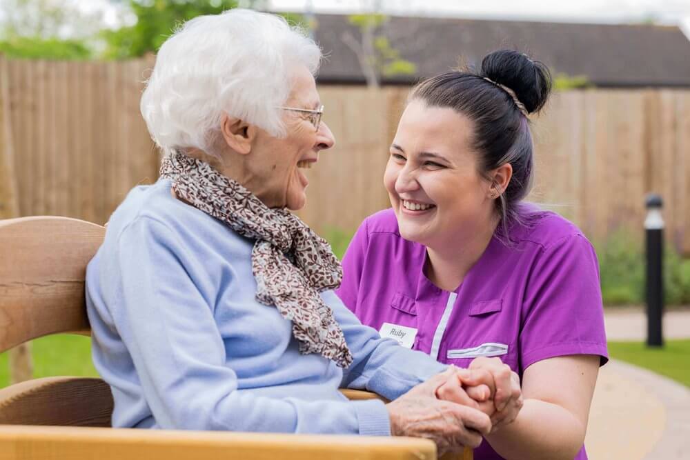 Care staff enjoying a moment with a resident outdoors.