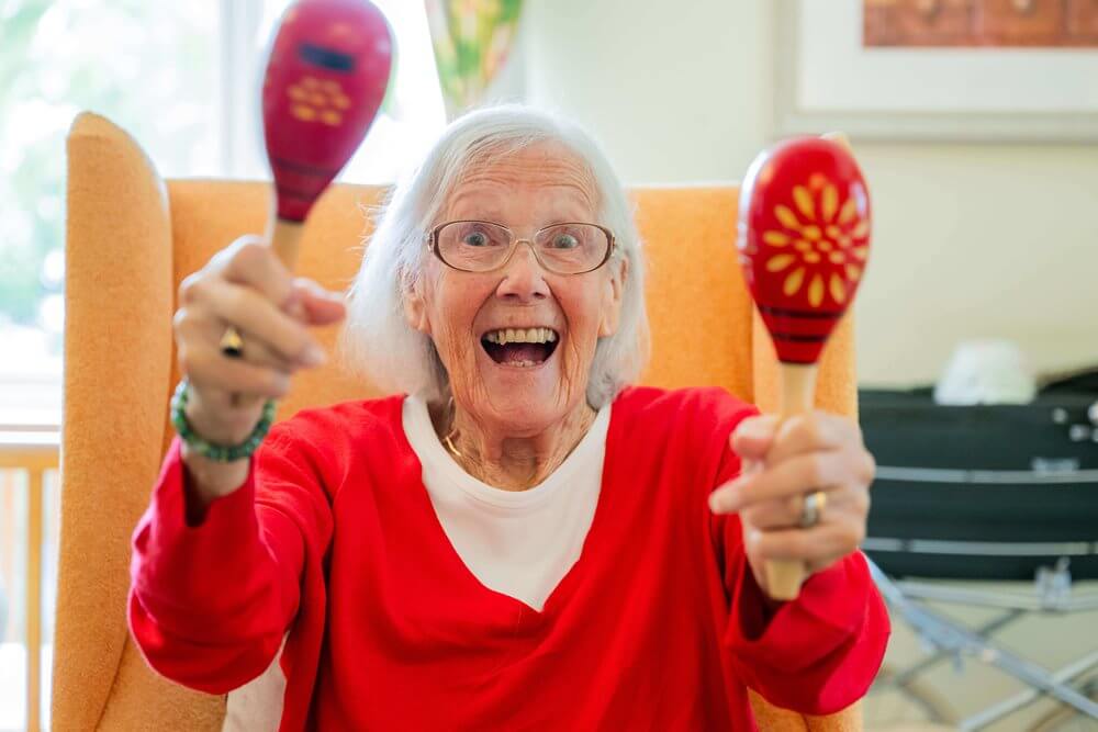 Elderly woman joyfully playing maracas.