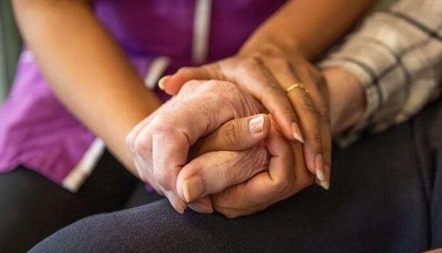 Caregiver and resident holding hands