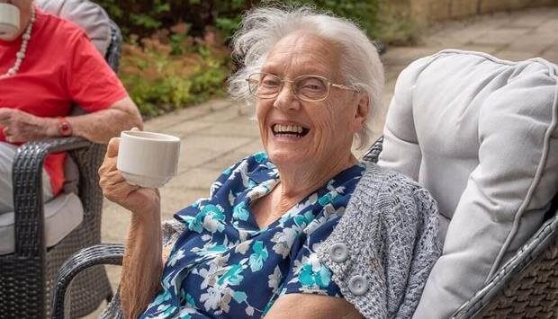 Smiling elderly woman enjoying a drink outdoors
