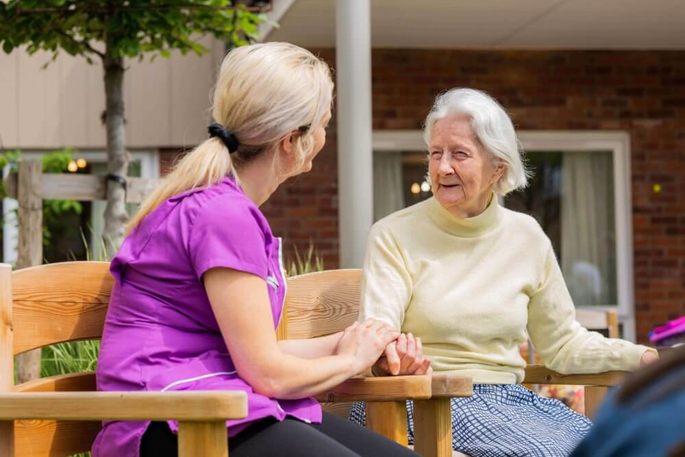 Care staff smiling and interacting with a resident outdoors.