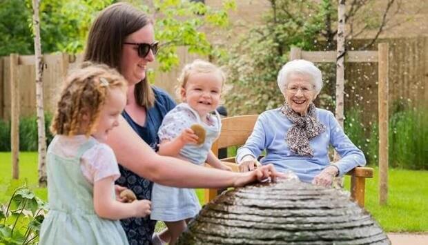 Elderly woman with children in garden area.