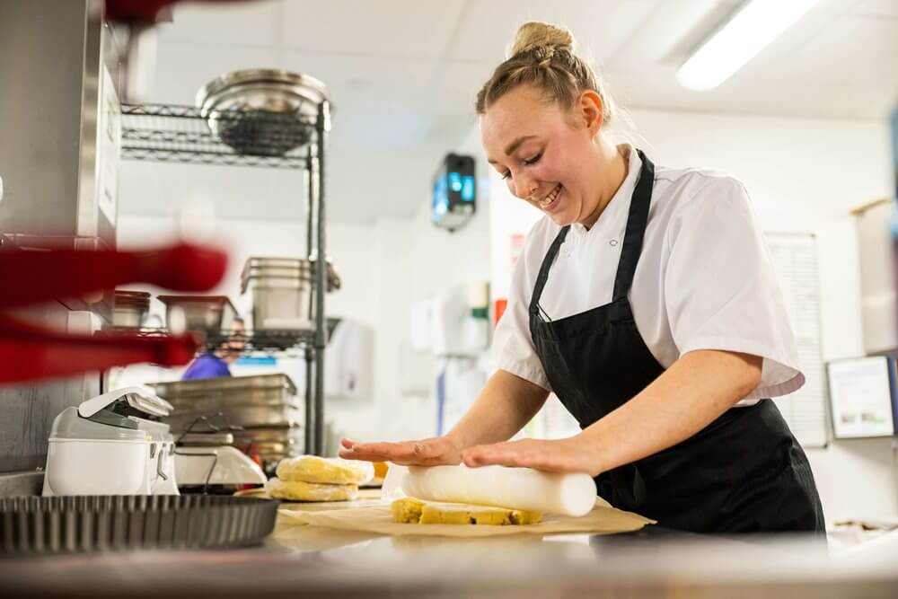 Staff member preparing food in the kitchen.